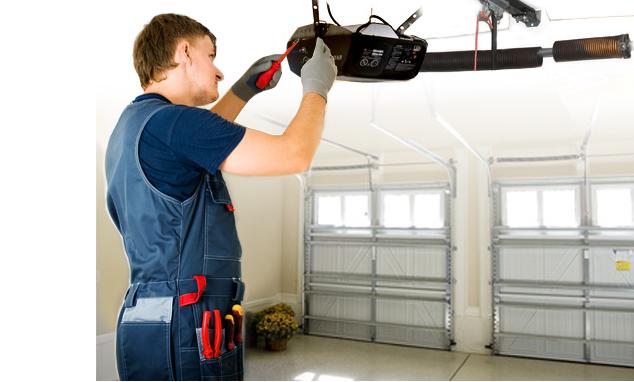 A man in blue work clothes working on garage door.