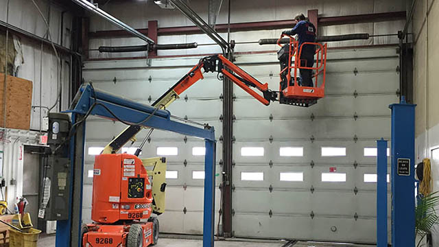 A man in an orange cherry-picker is working on the wall.